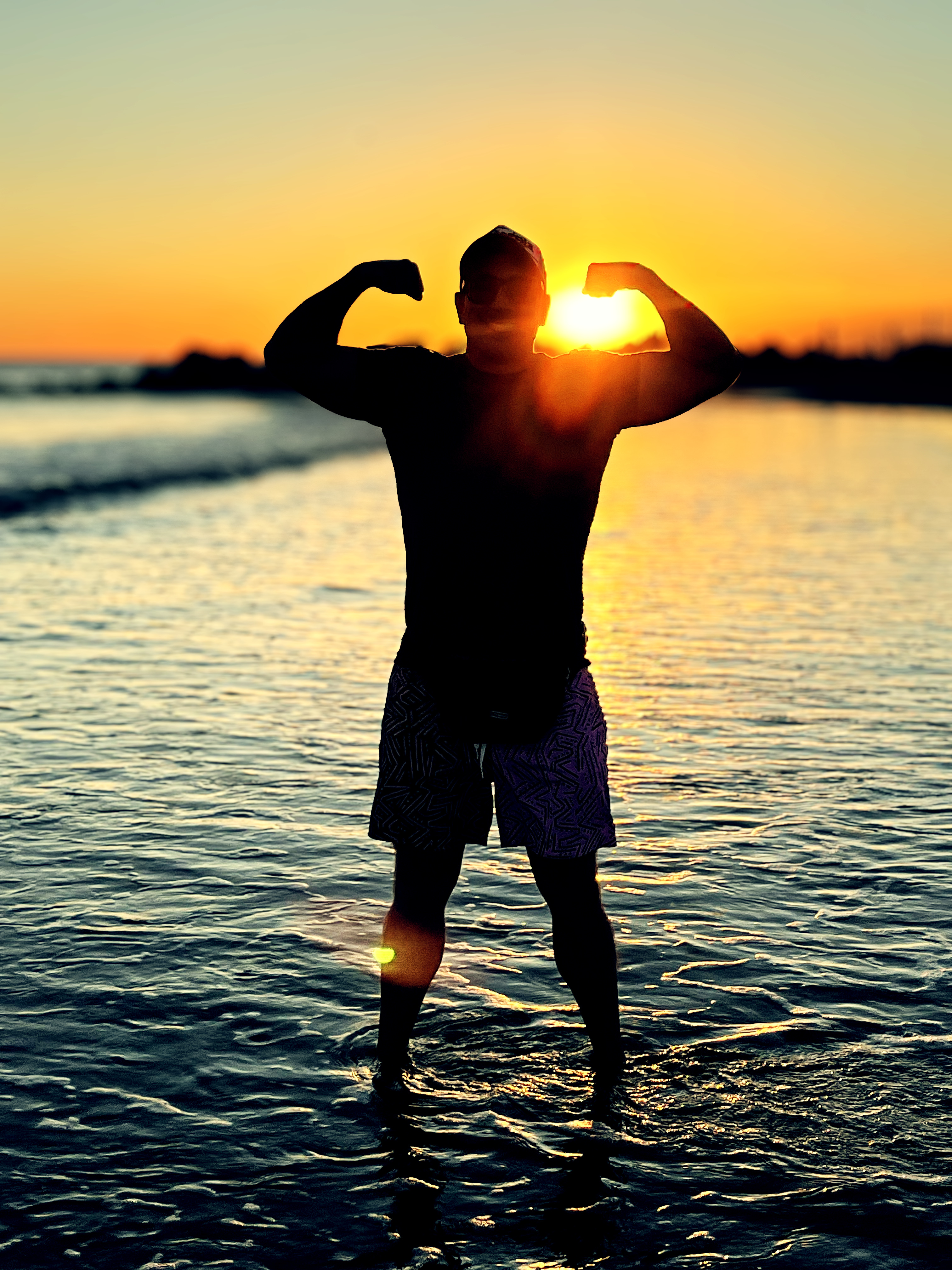 Man standing on beach flexing muscles