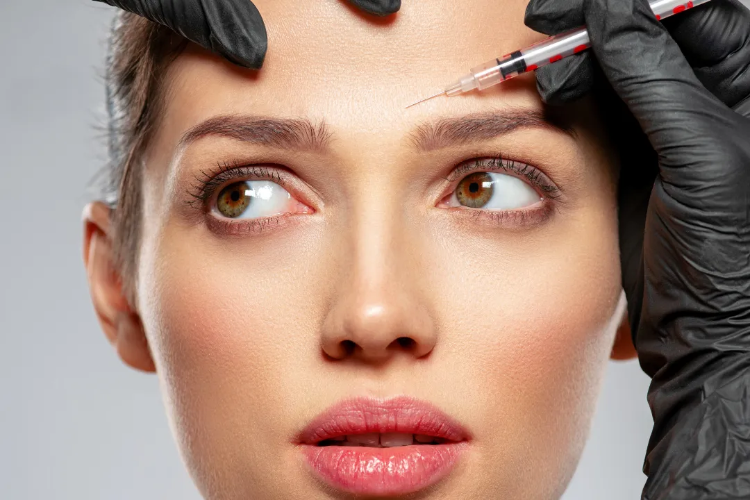 A woman receiving Botox or Dysport injections in her forehead area.