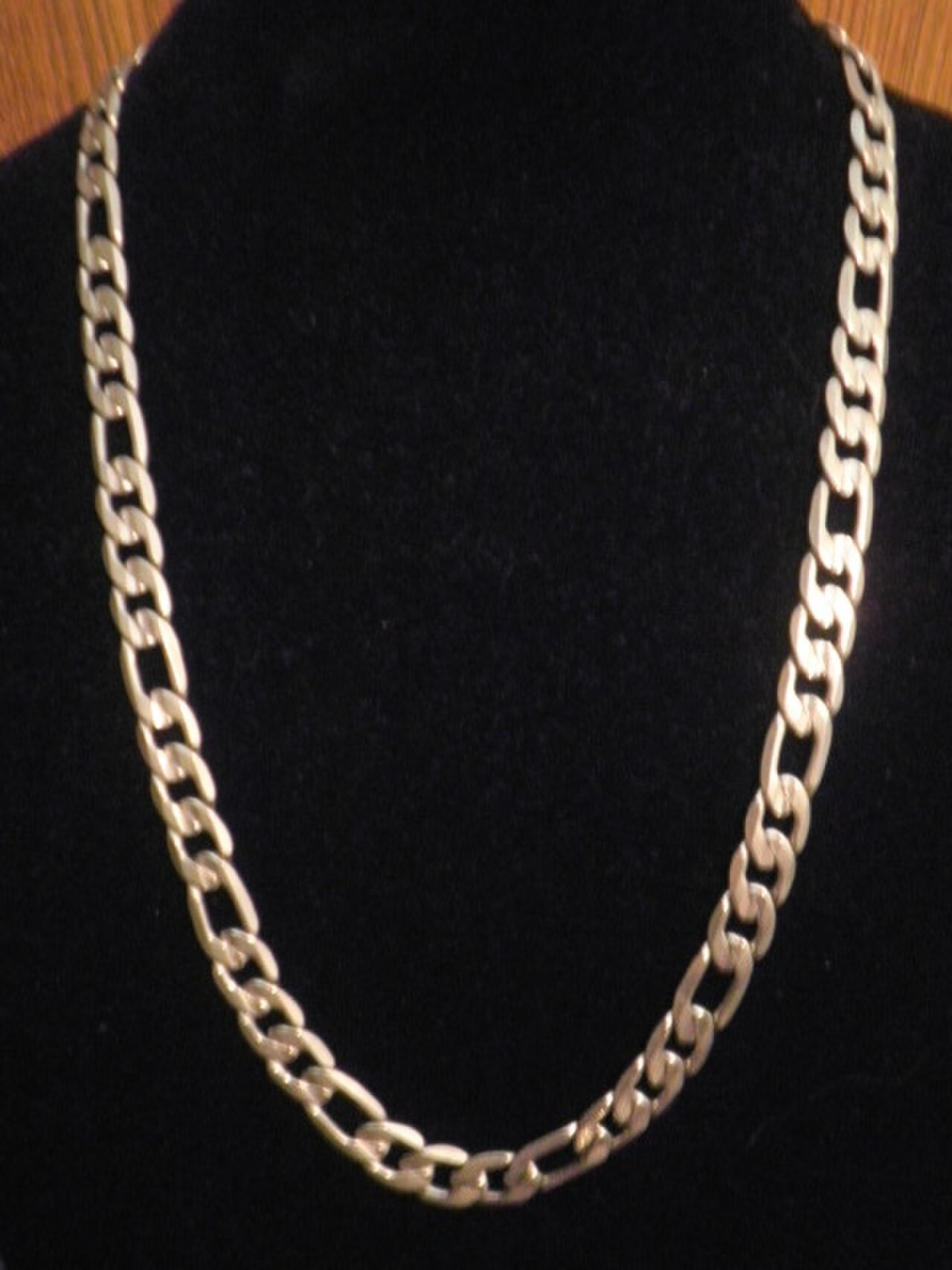 Thick gold men's curb-link chain necklace displayed on a bust