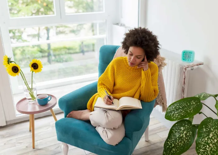 A close-up of a hand arranging gold-embossed invitation cards on a marble table, with a luxury watch and a glass of sparkling water nearby. The setting is refined, with soft natural light and a focus on tactile, premium materials.