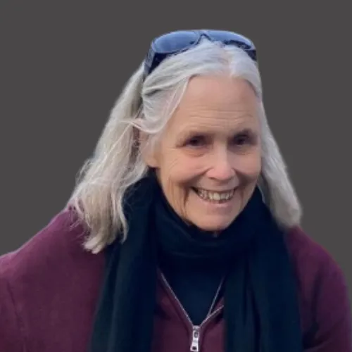 A charismatic man in his 30s with dark skin and a close-cropped beard, wearing a crisp white shirt and gold cufflinks, seated in a velvet armchair. The setting is a high-rise office with panoramic city views.
