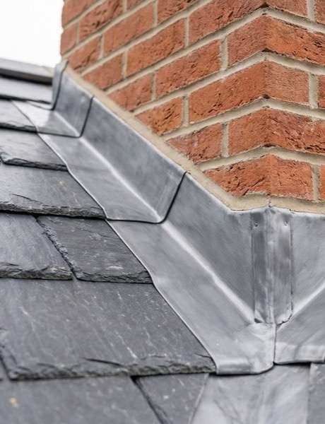 Lead flashing and slate tiles around a chimney stack on a residential roof