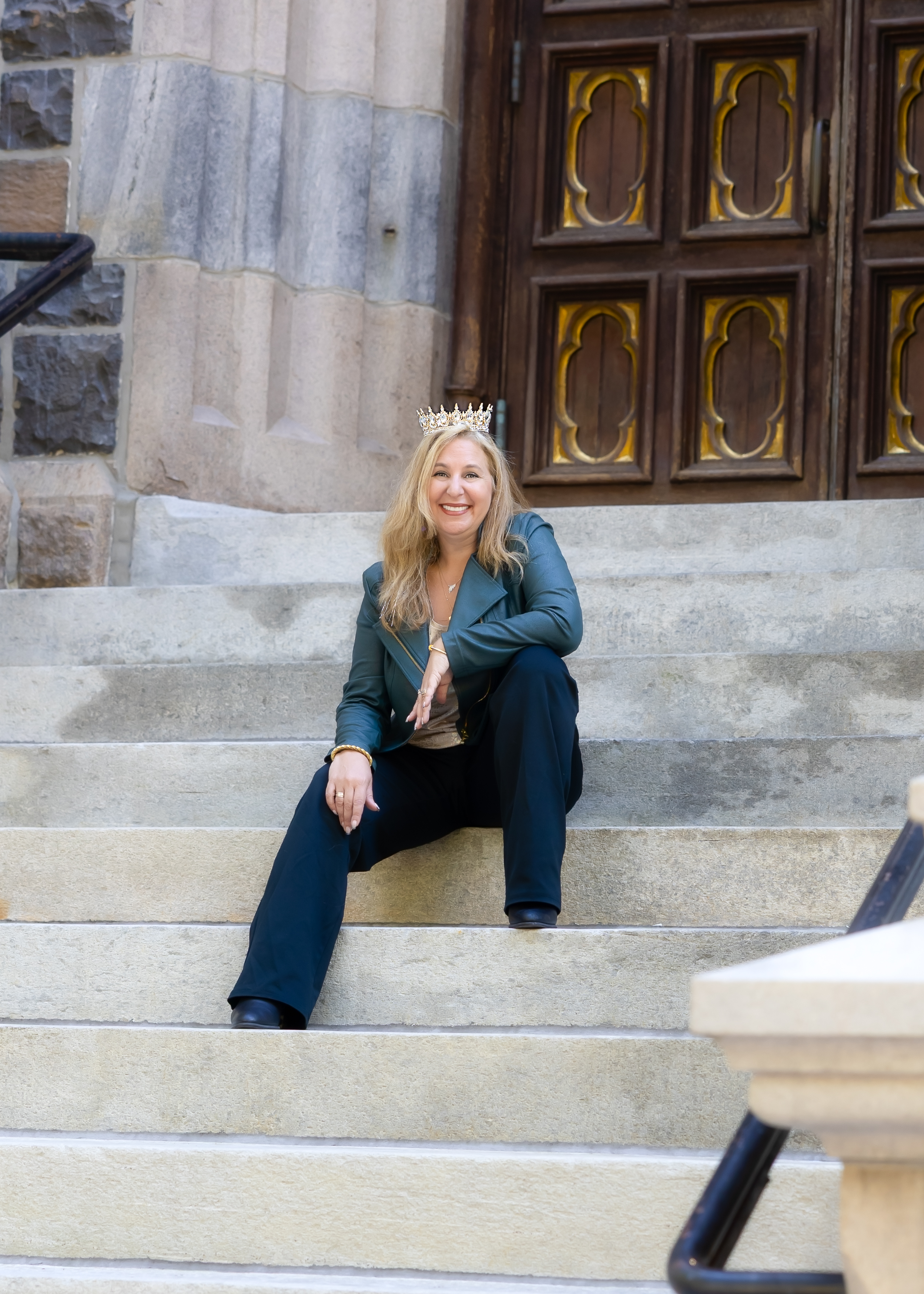Cheryl, an experienced real estate coach, sits at a glass desk with property blueprints and a laptop, smiling confidently. The background features framed awards and a bookshelf with real estate books, conveying expertise and warmth.