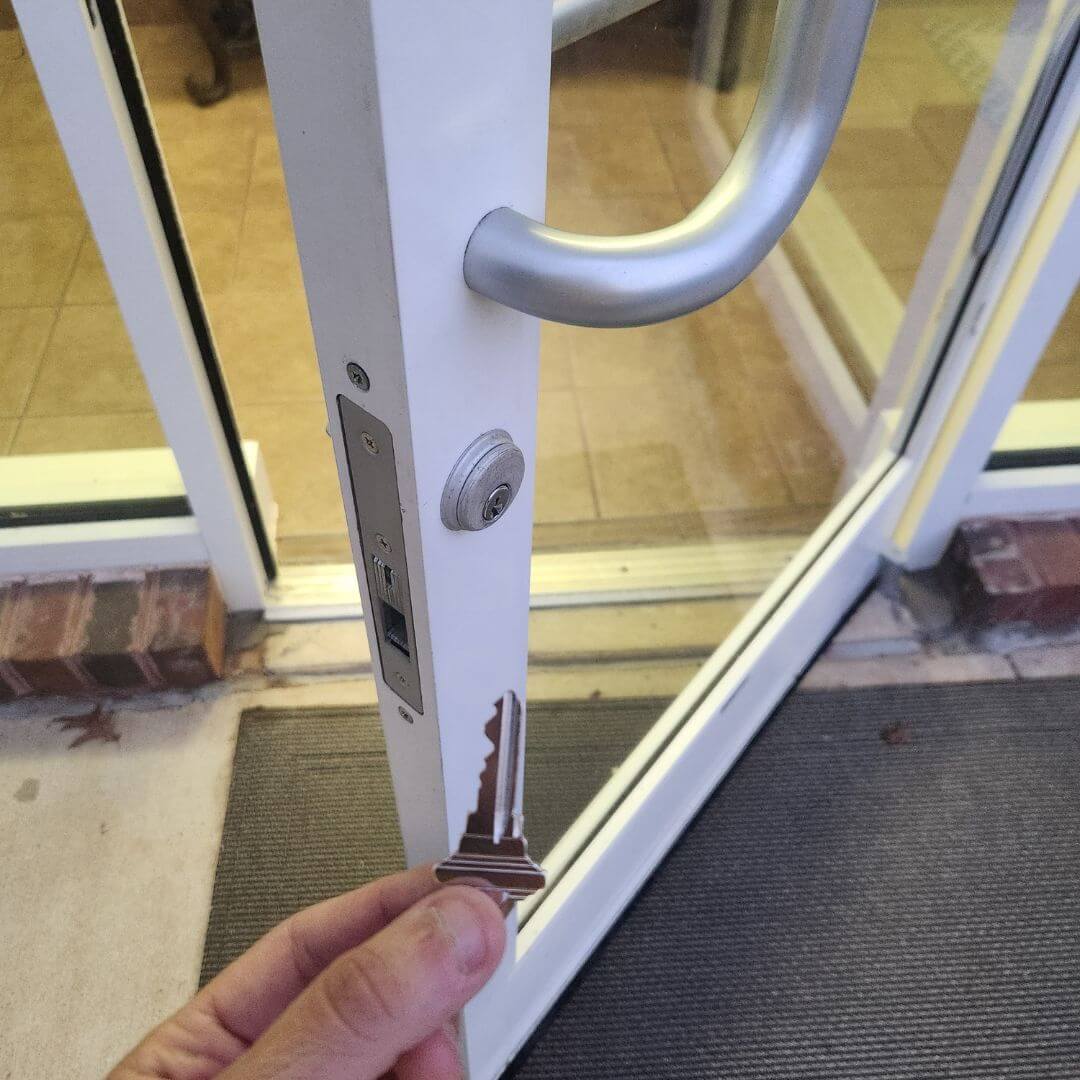Commercial locksmith service with key in hand at business entrance