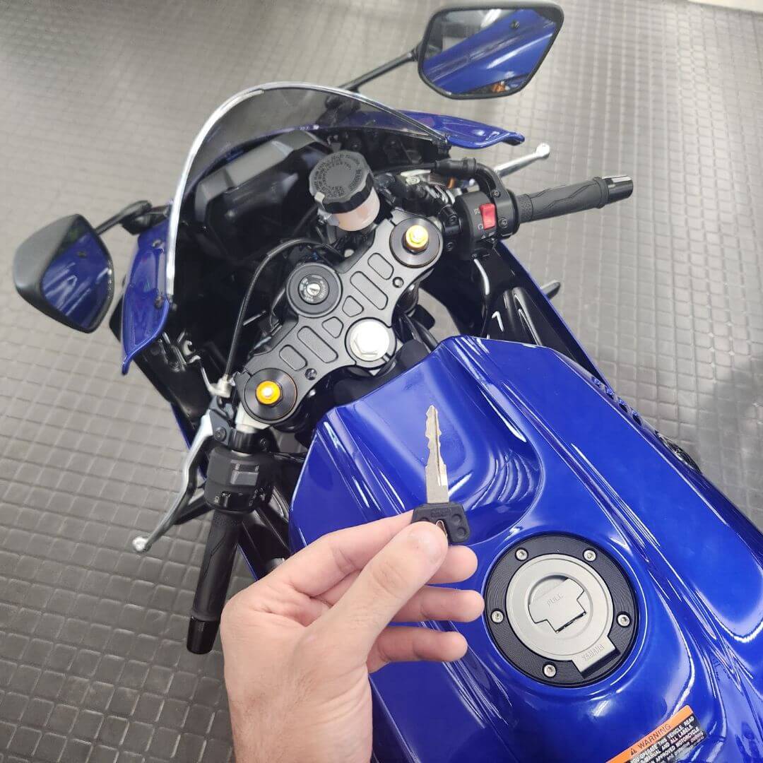 Mobile motorcycle key replacement with key in hand beside motorcycle