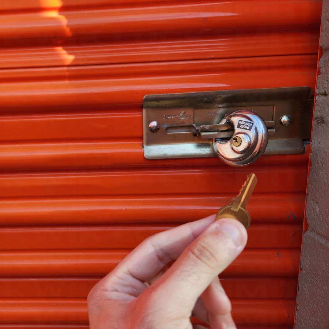 Storage unit lock opened with key in hand at unit door