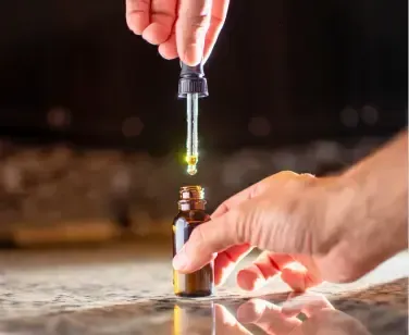 Cannabis tincture oil dropper dispensing liquid into glass bottle