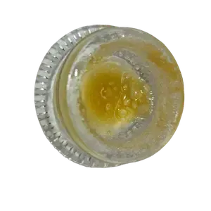 Cannabis concentrate in a clear glass container, golden-yellow live resin with a sticky texture.