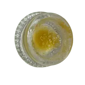 Cannabis concentrate in a clear glass container, golden-yellow live resin with a sticky texture.