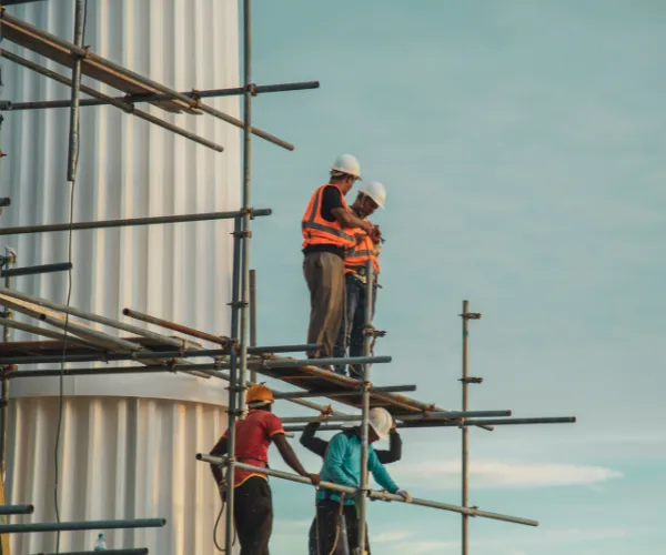 Construction worker in Paksitan skillfully assembling scaffolding at a bustling building site