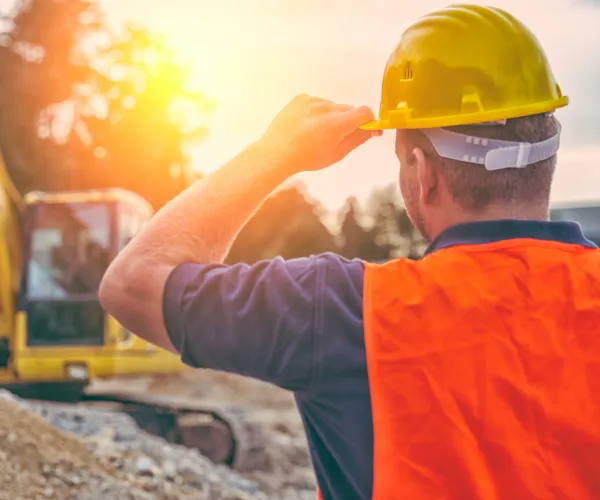 Worker at a Faisalabad construction site carrying bricks and materials for a new housing estate.