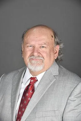 Professional headshot of James William (Jim Bill) Harvey, Senior Vice President at Centurion Insurance Services, wearing a light gray suit, white shirt, and red patterned tie against a gray background.