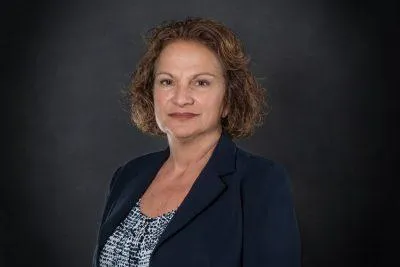 Professional headshot of Mary H. Meredith, Executive Assistant at Centurion Insurance Services, wearing a navy blazer and patterned blouse, posed in front of a dark studio background.