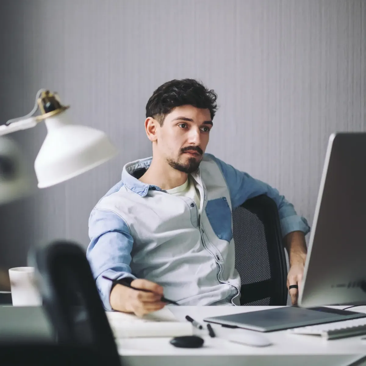 Young professional working at a desk with a laptop and documents, representing Employee Benefits Services offered by Centurion Insurance Services.