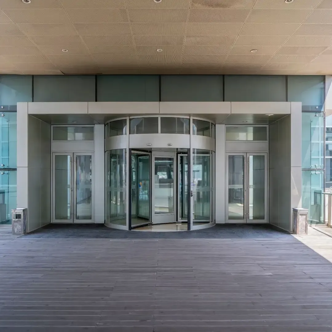 Modern office building entrance with revolving glass doors, promoting Property & Casualty Insurance services from Centurion Insurance Services.
