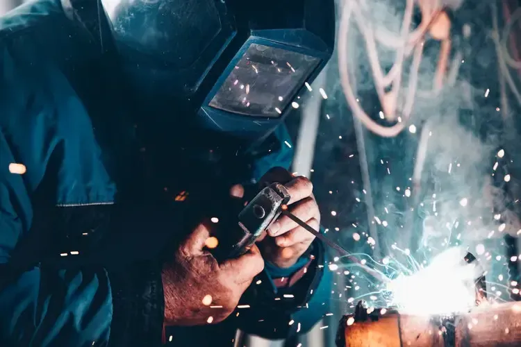Close-up of a welder in protective gear working with sparks flying, representing Centurion Insurance Services’ expertise in providing property and casualty coverage for the manufacturing industry.