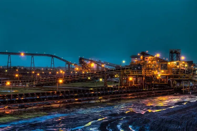 Illuminated industrial facility at night with conveyor systems and infrastructure, representing Centurion Insurance Services’ property and casualty expertise in the energy sector.