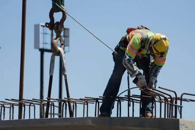 Construction worker in safety gear securing steel reinforcement bars on a job site, illustrating Centurion Insurance Services’ loss control and risk management expertise.