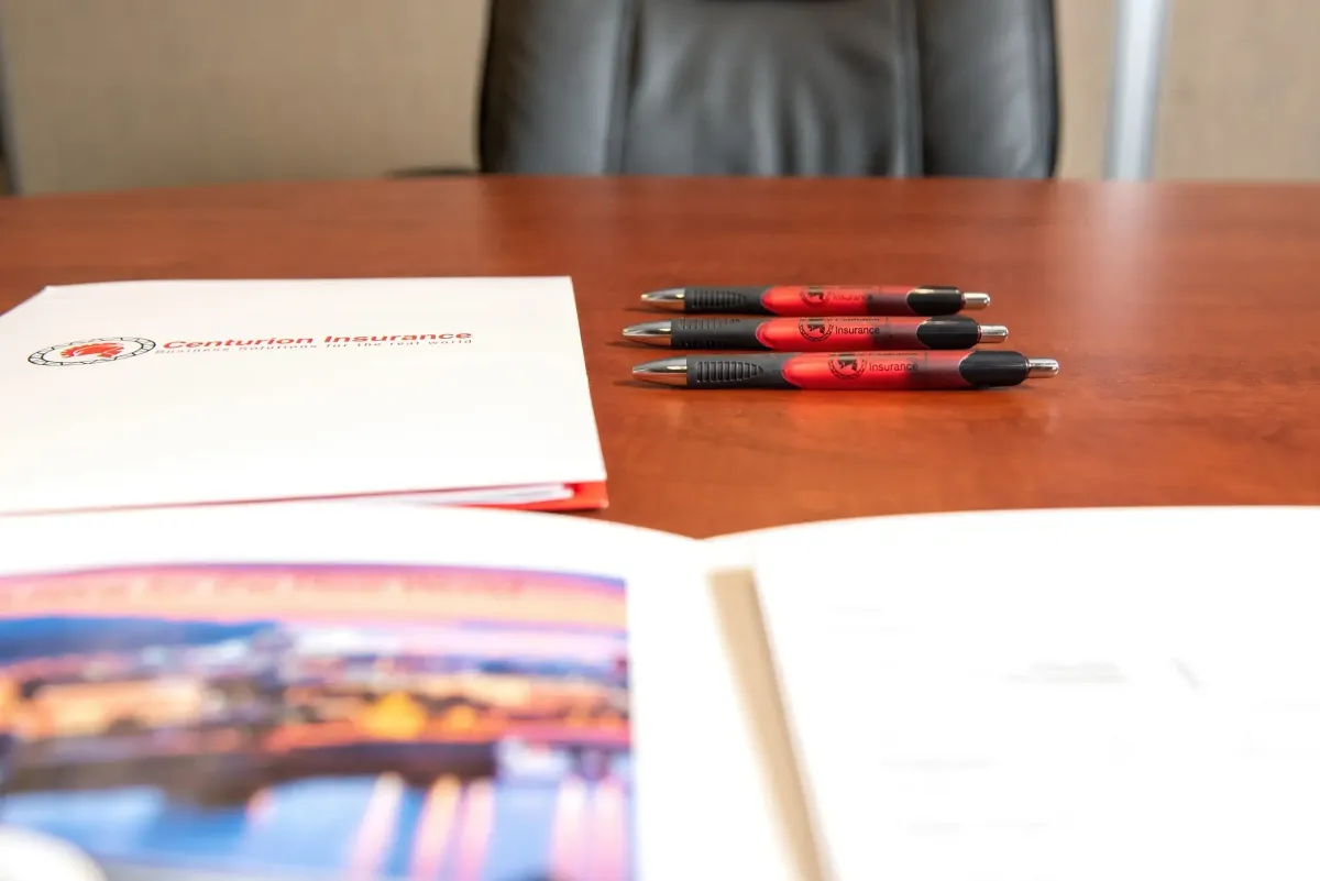 Close-up of Centurion Insurance Services-branded pens and employee benefits folders on a conference table, representing the company’s value-added services like educational materials and wellness initiatives.