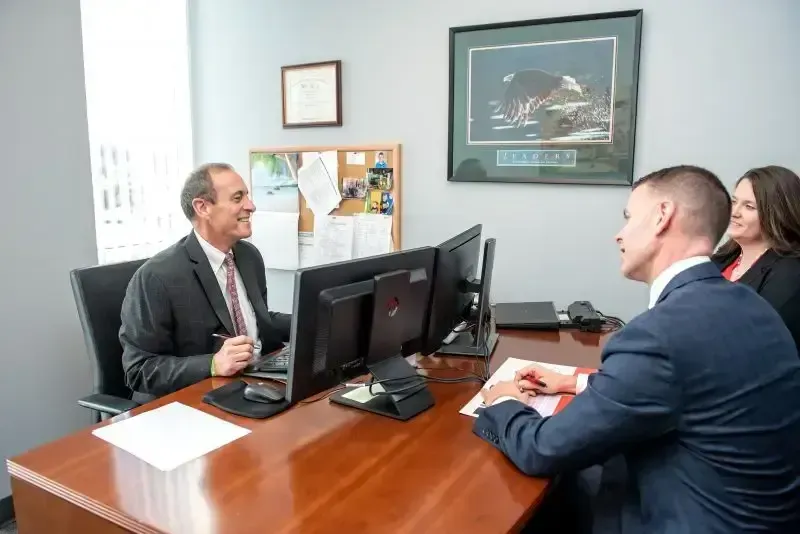 Centurion team members in a professional office meeting with clients, representing personalized employee benefits plan design and consulting services.