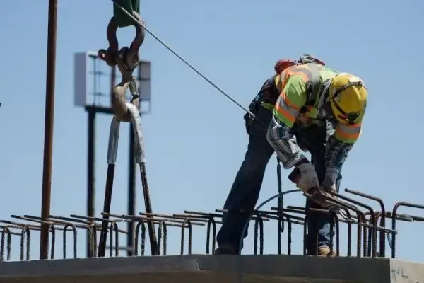 Construction worker in safety gear securing steel reinforcement bars on a concrete structure, representing Centurion Insurance Services’ practical risk management and loss control tools.