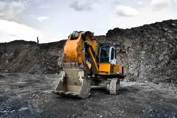 Yellow excavator parked at a rocky construction or mining site, symbolizing Centurion Insurance Services’ loss control support for high-risk industries.