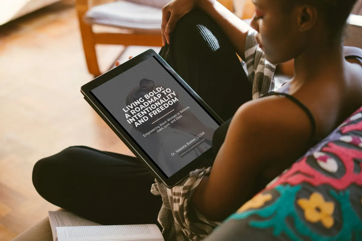 Black woman reading the Living BOLD eBook by Dr. Natasha Booker — a free guide for ambitious Black women seeking clarity, purpose, and personal growth