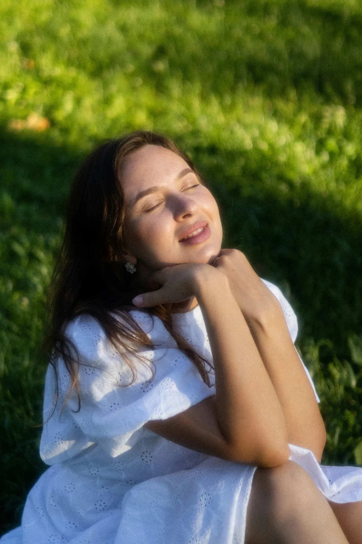 A relaxed person smiling with eyes closed outdoors