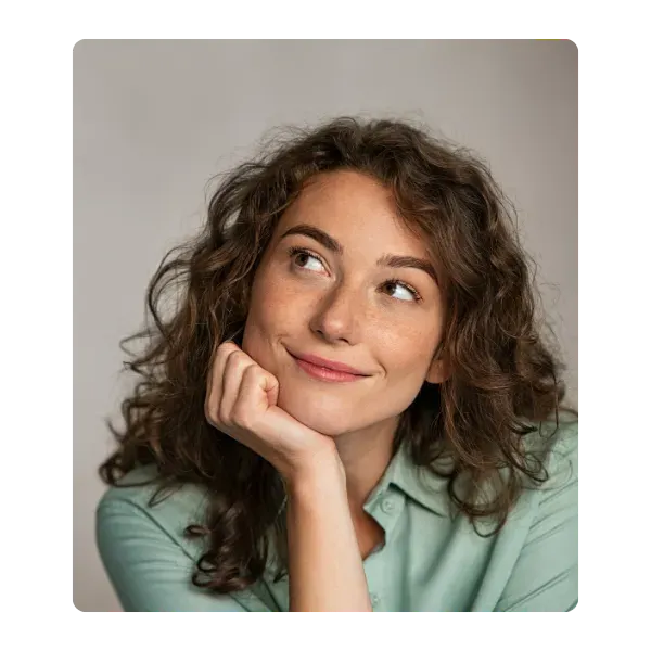Thoughtful woman with curly hair and a green shirt, contemplating body sugaring certification options.