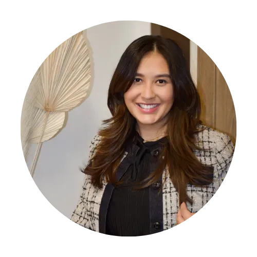 Smiling woman in a stylish outfit, standing against a neutral background with decorative plant elements, representing the Love2Sugar community and its focus on sugaring education and inspiration.