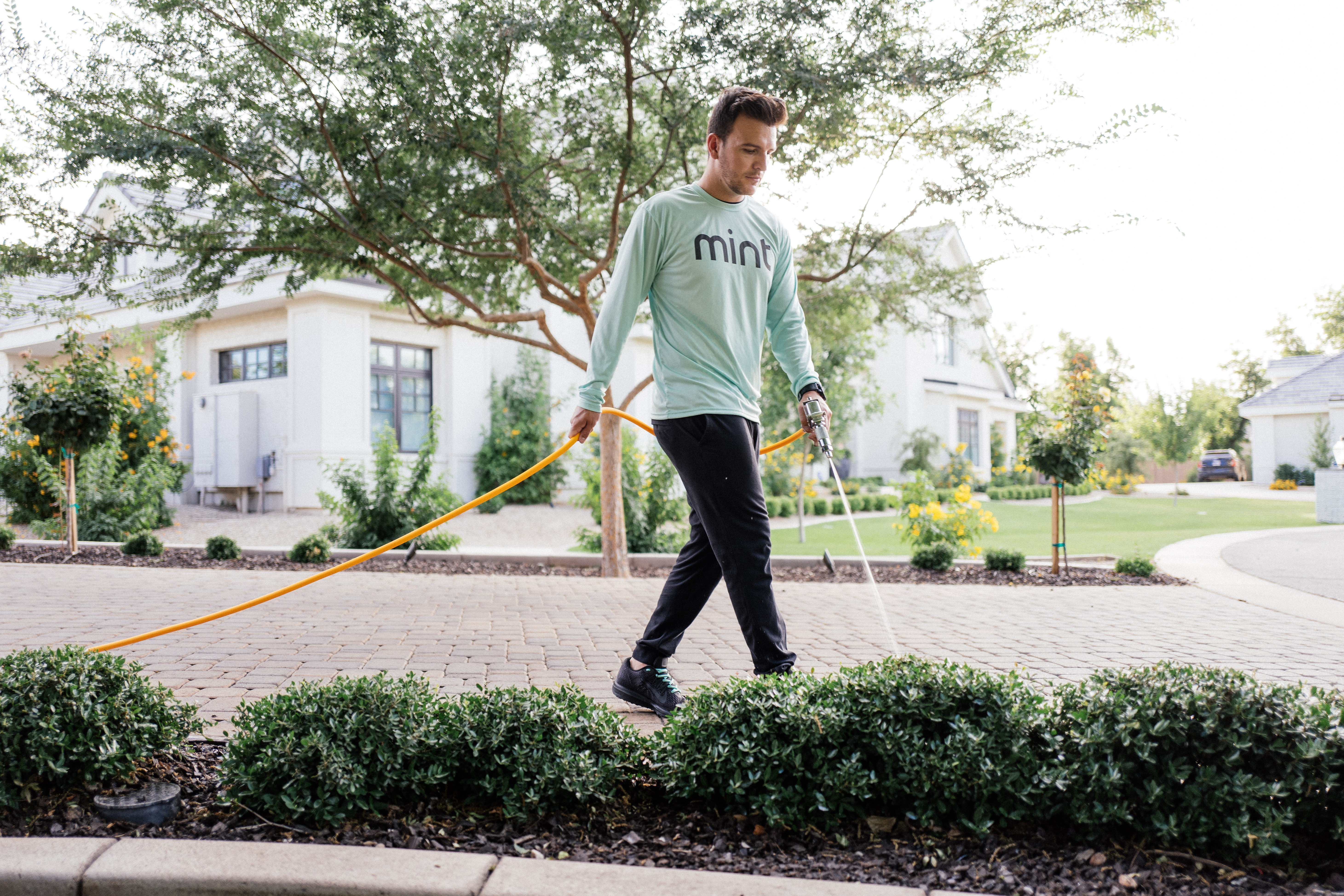 Mint Pest Control technician applying an exterior pest-control treatment to a residential lawn in Fishers