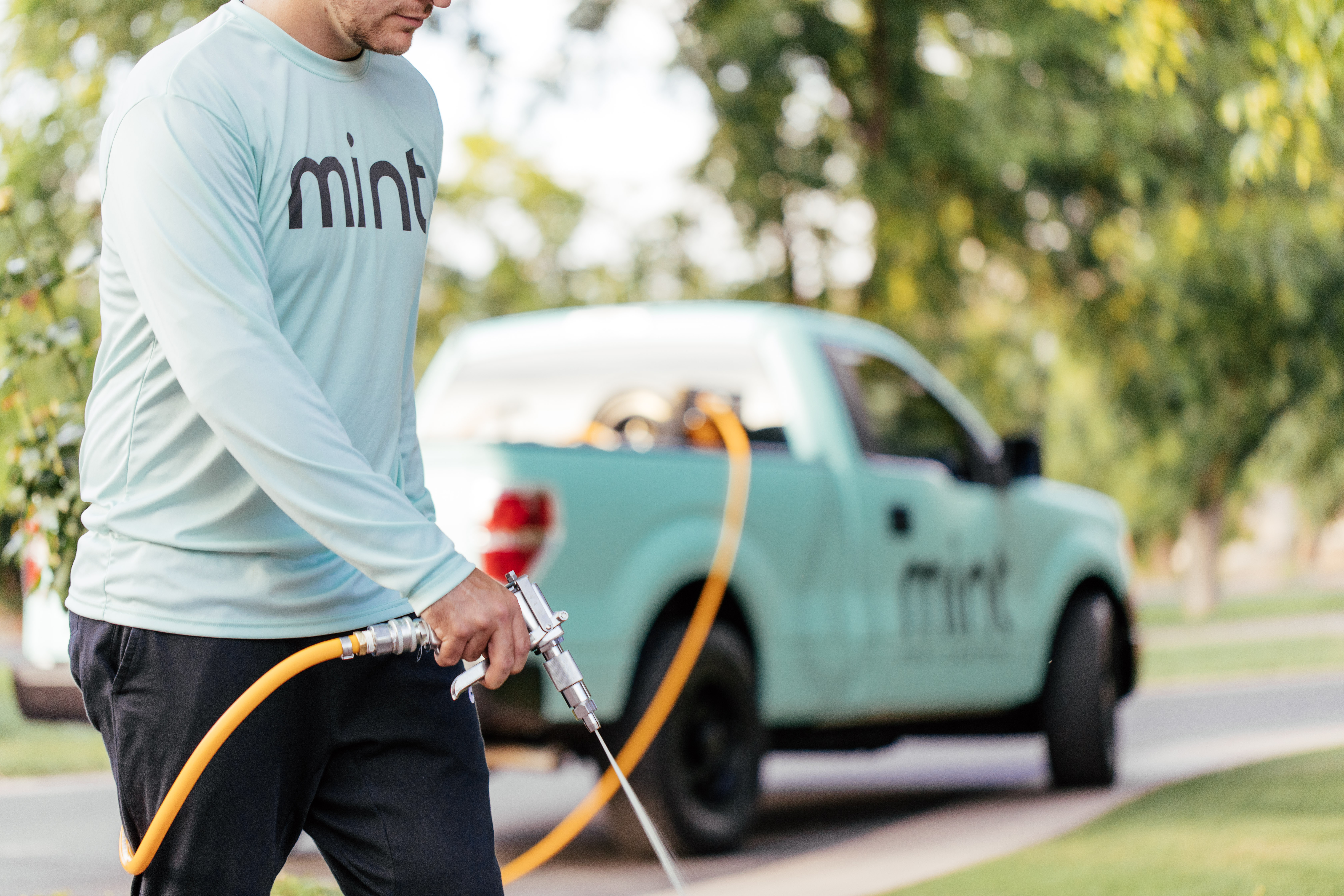 Mint Pest Control technician applying an exterior pest-control treatment at a Fishers property