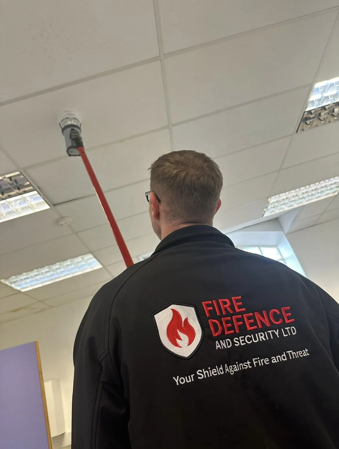 Security technician installing a CCTV camera on commercial building exterior – Fire Defence and Security