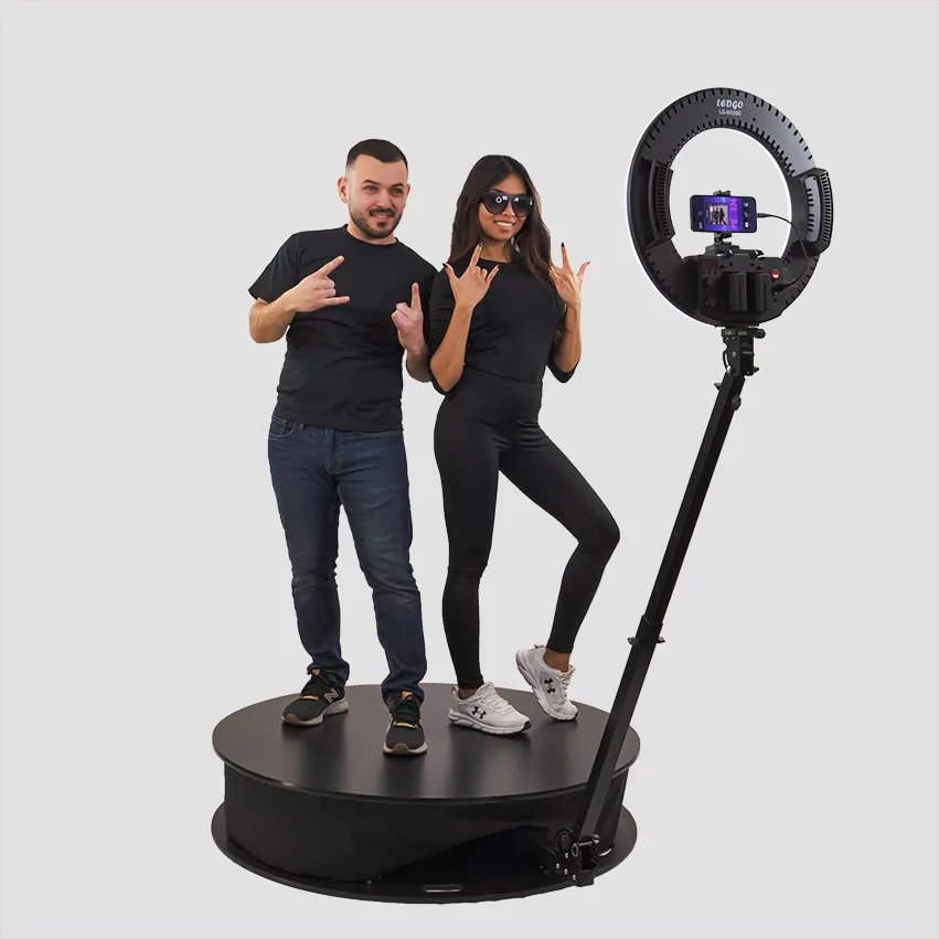 A man and a woman having fun on a 360 photobooth against a white background