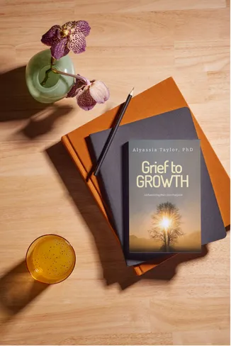 Grief to Growth book on a table with journal and glass of water