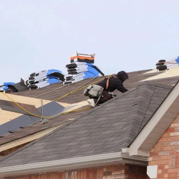 Roofer laying new shingles on a roof during roof replacement