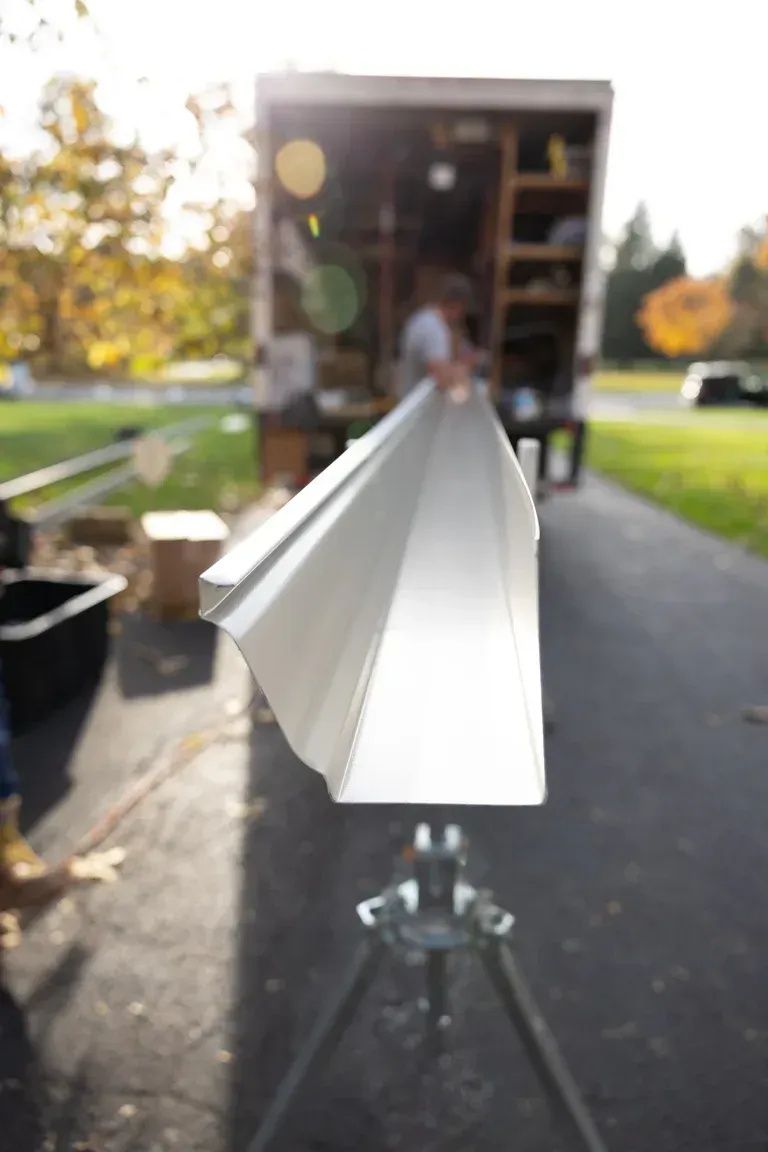 Gutters rolling out of truck being cut to size