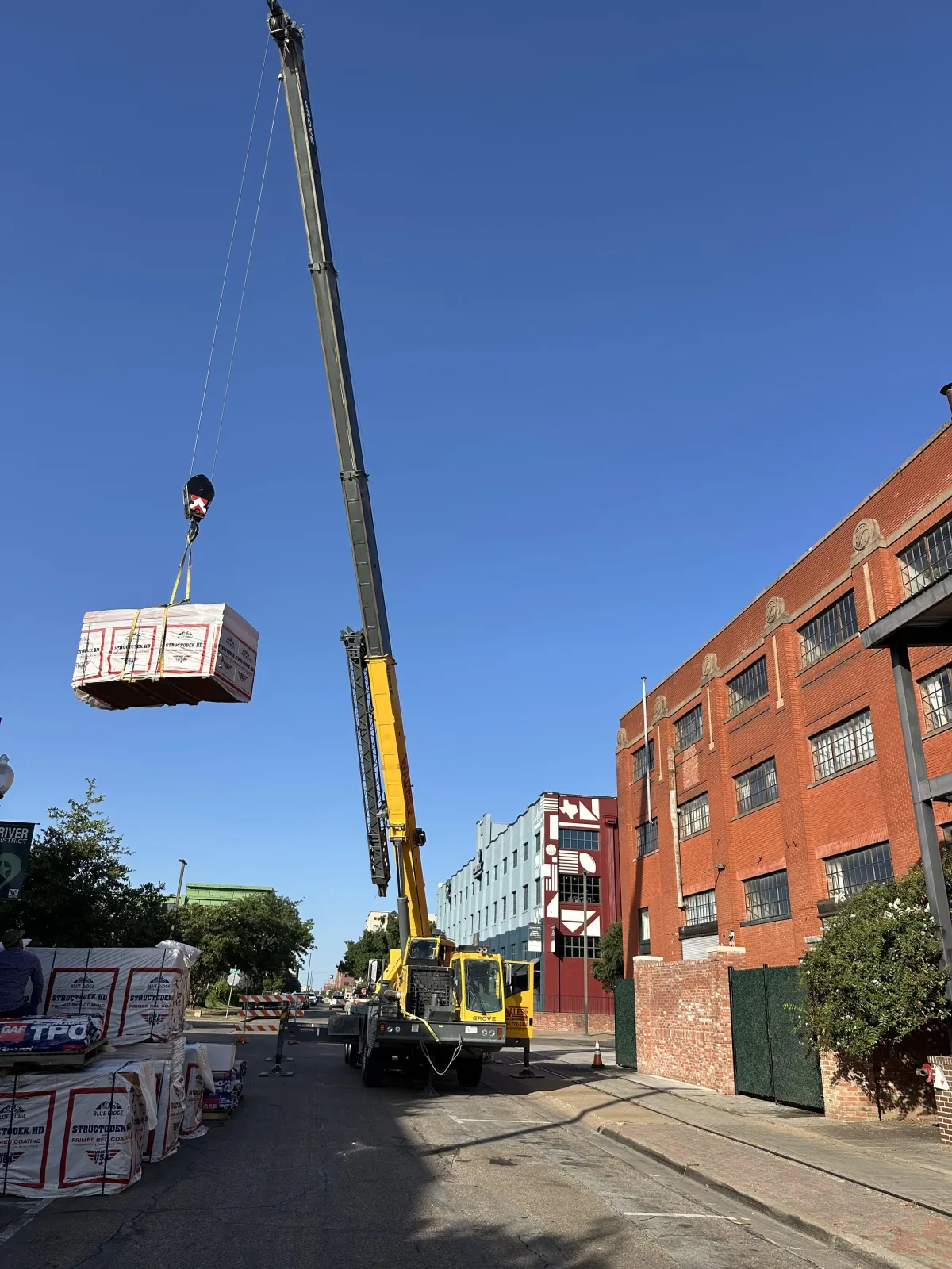 Large boom lifting up TPO shingles for a commercial roof in downtown Waco, Texas.