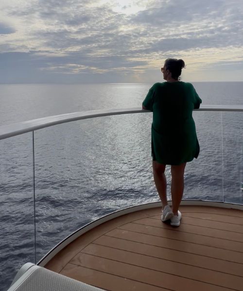 Danielle, founder and certified cruise travel agent at Royal Serene Travel, aboard a cruise ship at sunset