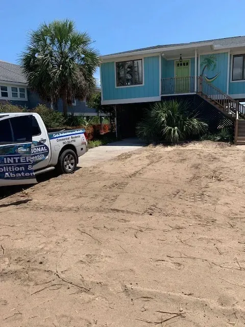 House demolition in Myrtle Beach SC featuring a cleared lot, construction equipment, and neighborhood scenery with palm trees.