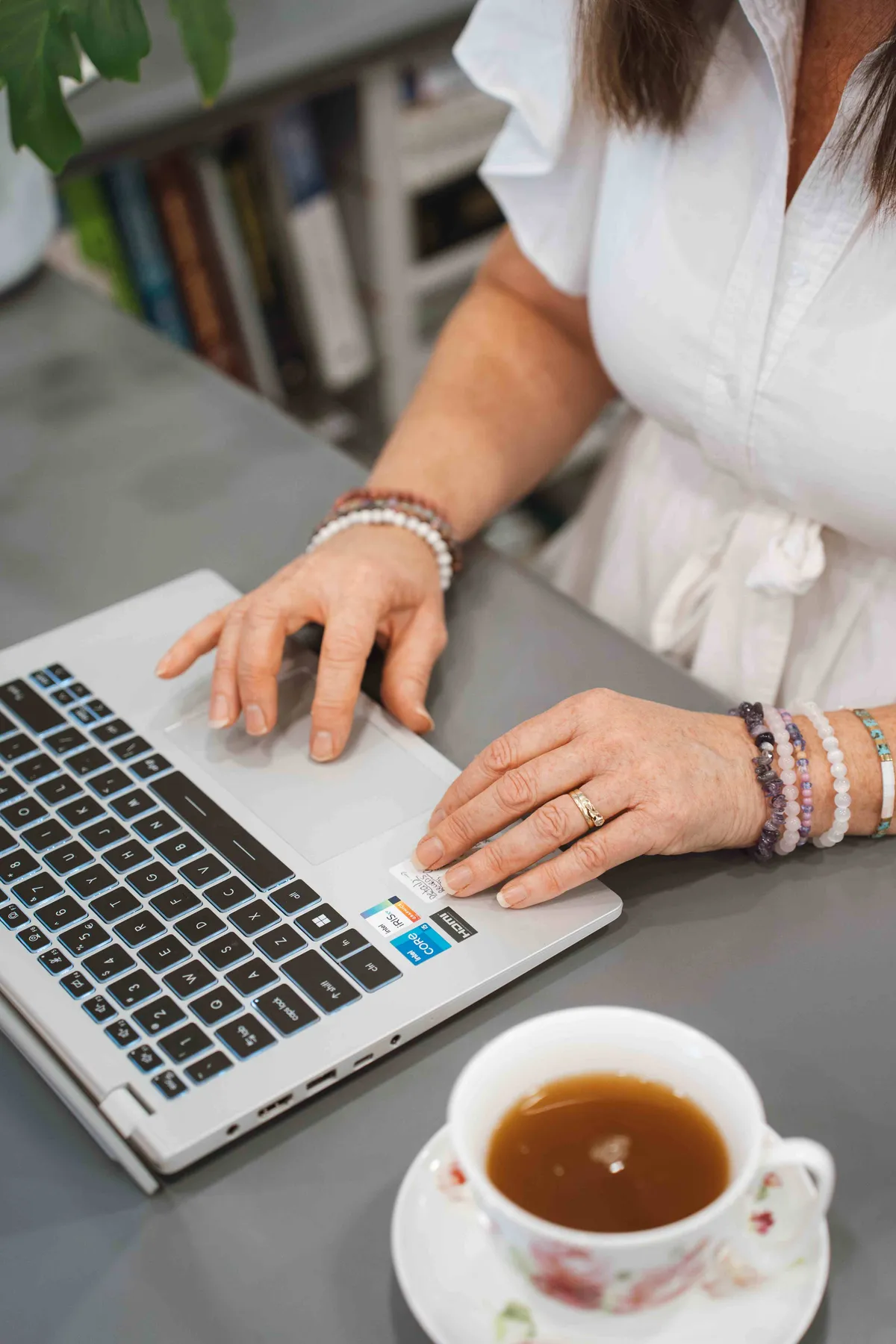 Hands typing on a laptop with a cup of coffee nearby
