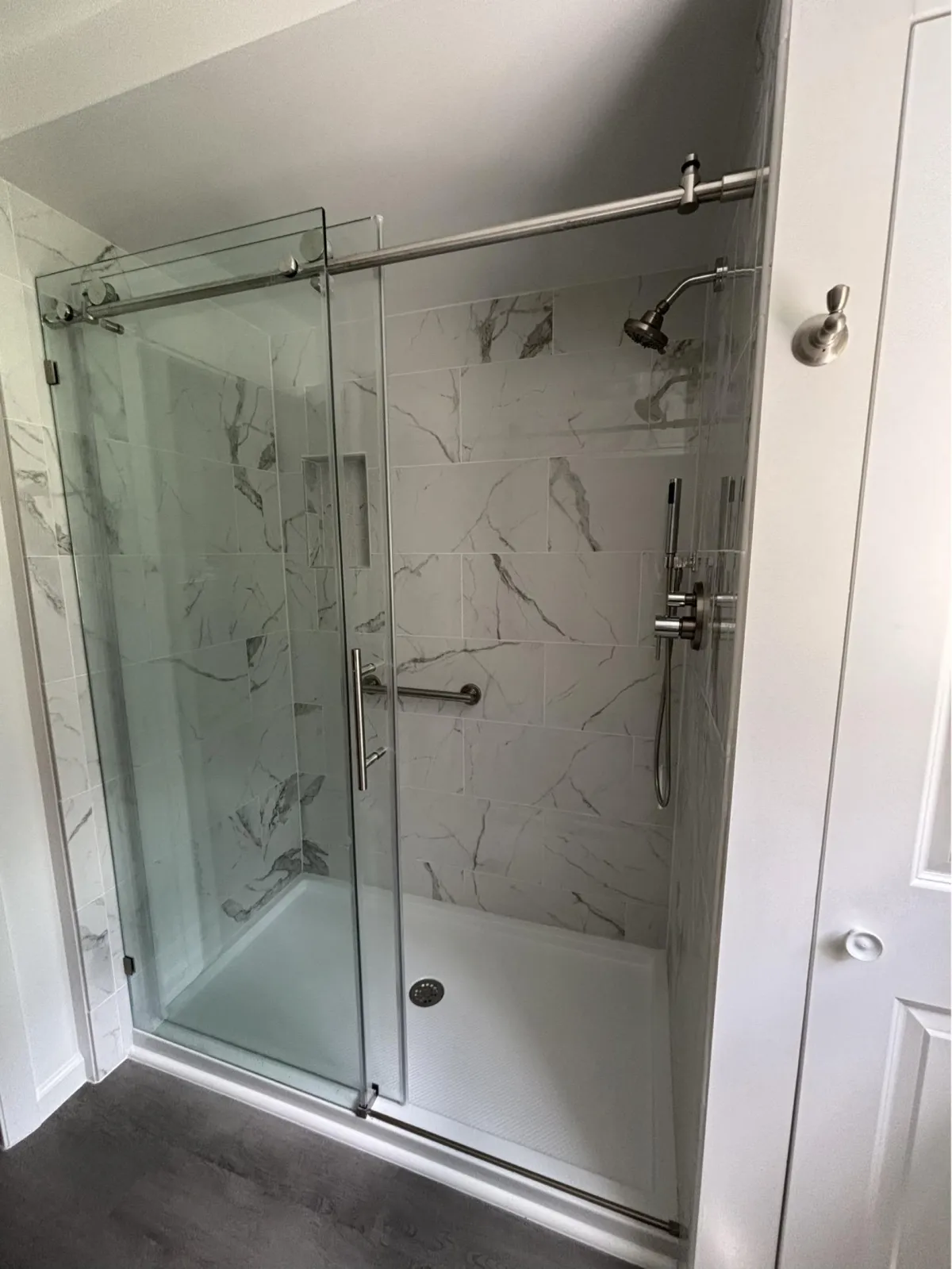 Frameless glass shower with marble tile walls and modern fixtures
