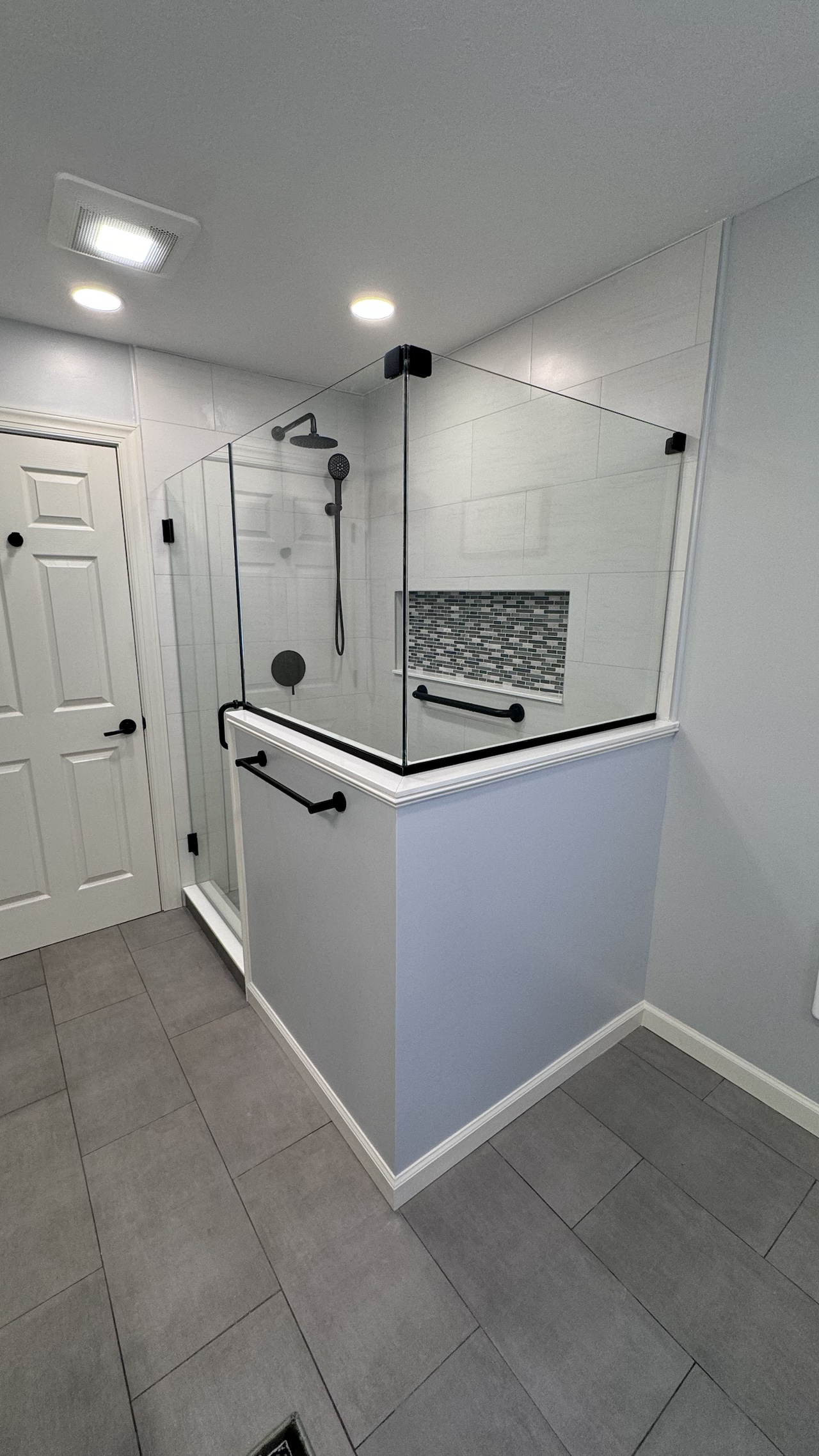 Modern walk-in shower with glass panels and black hardware fixtures