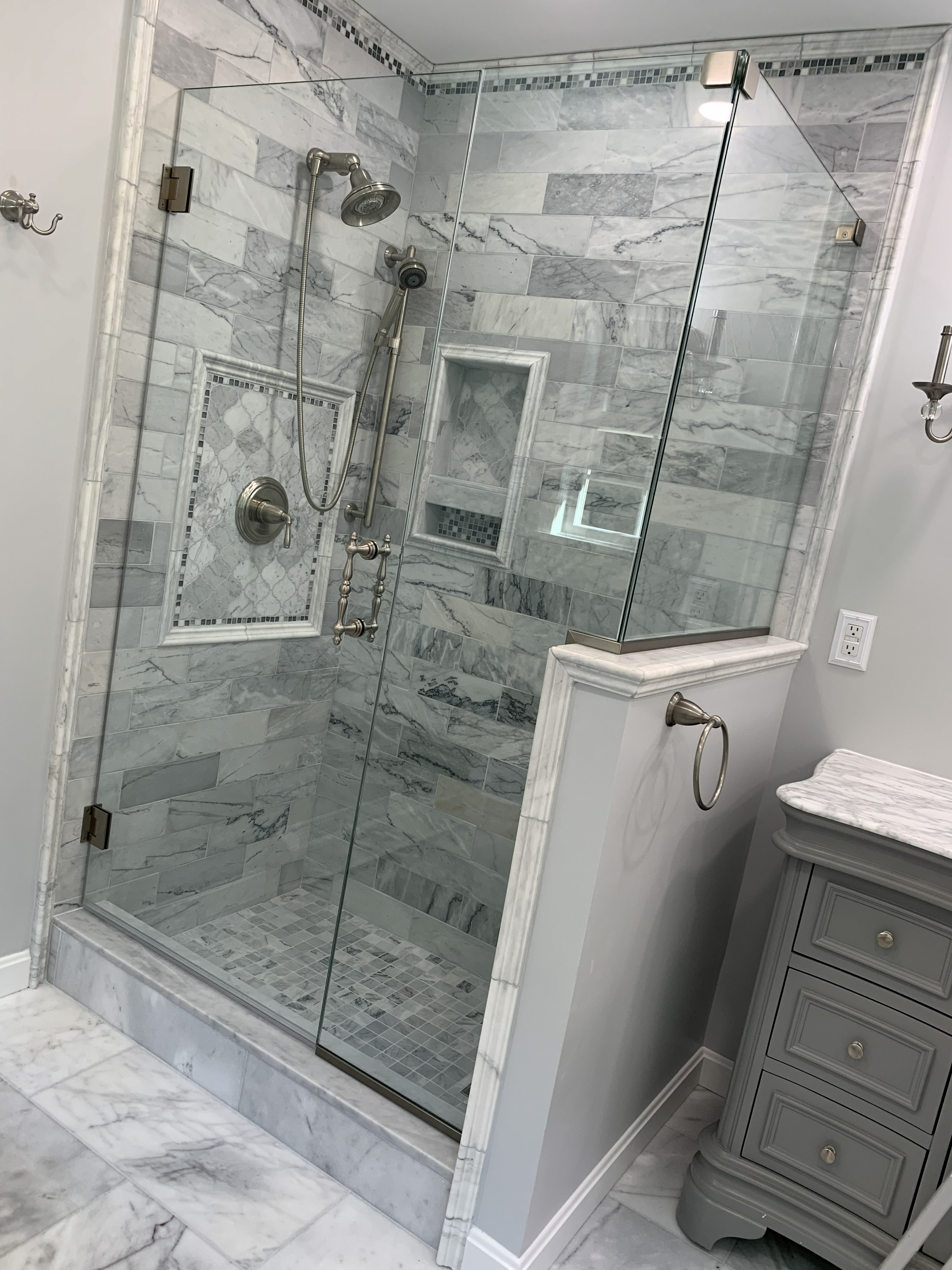 Bathroom remodel with marble tile shower, glass enclosure, and built-in nich