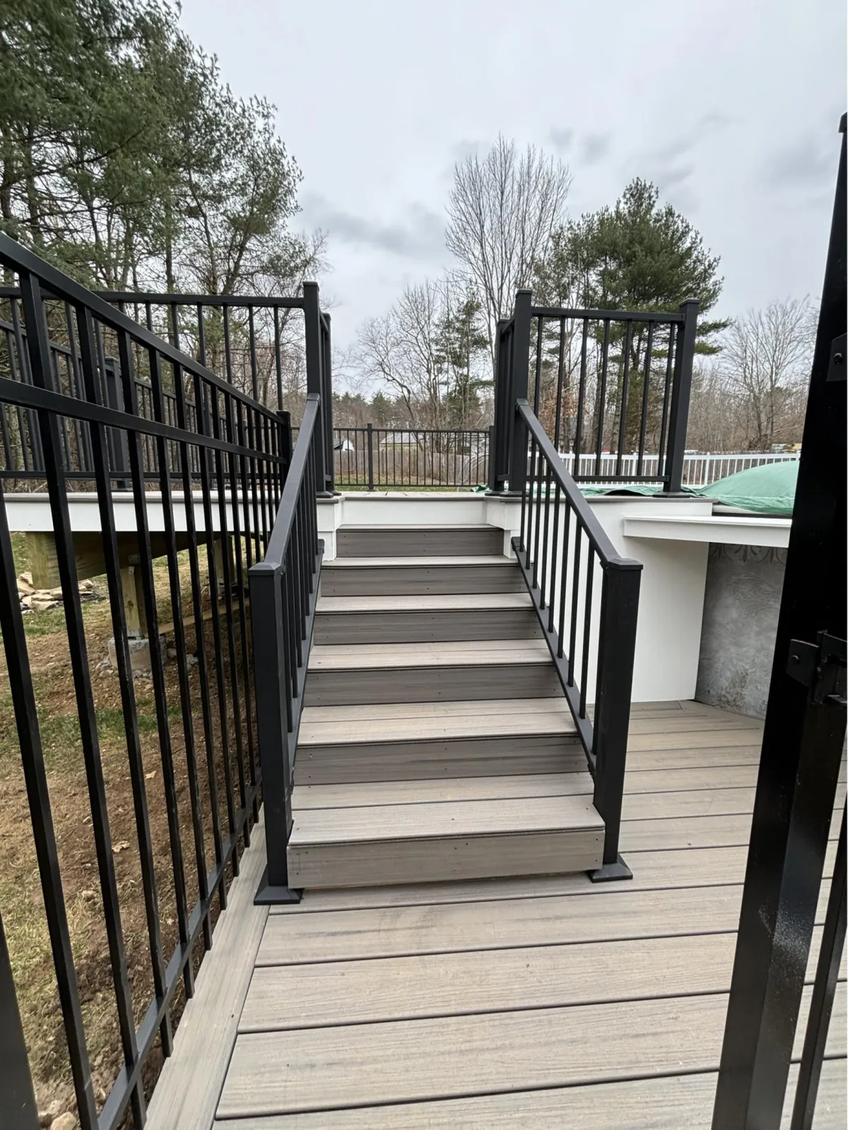 Composite deck stairs with black metal railings leading to upper deck