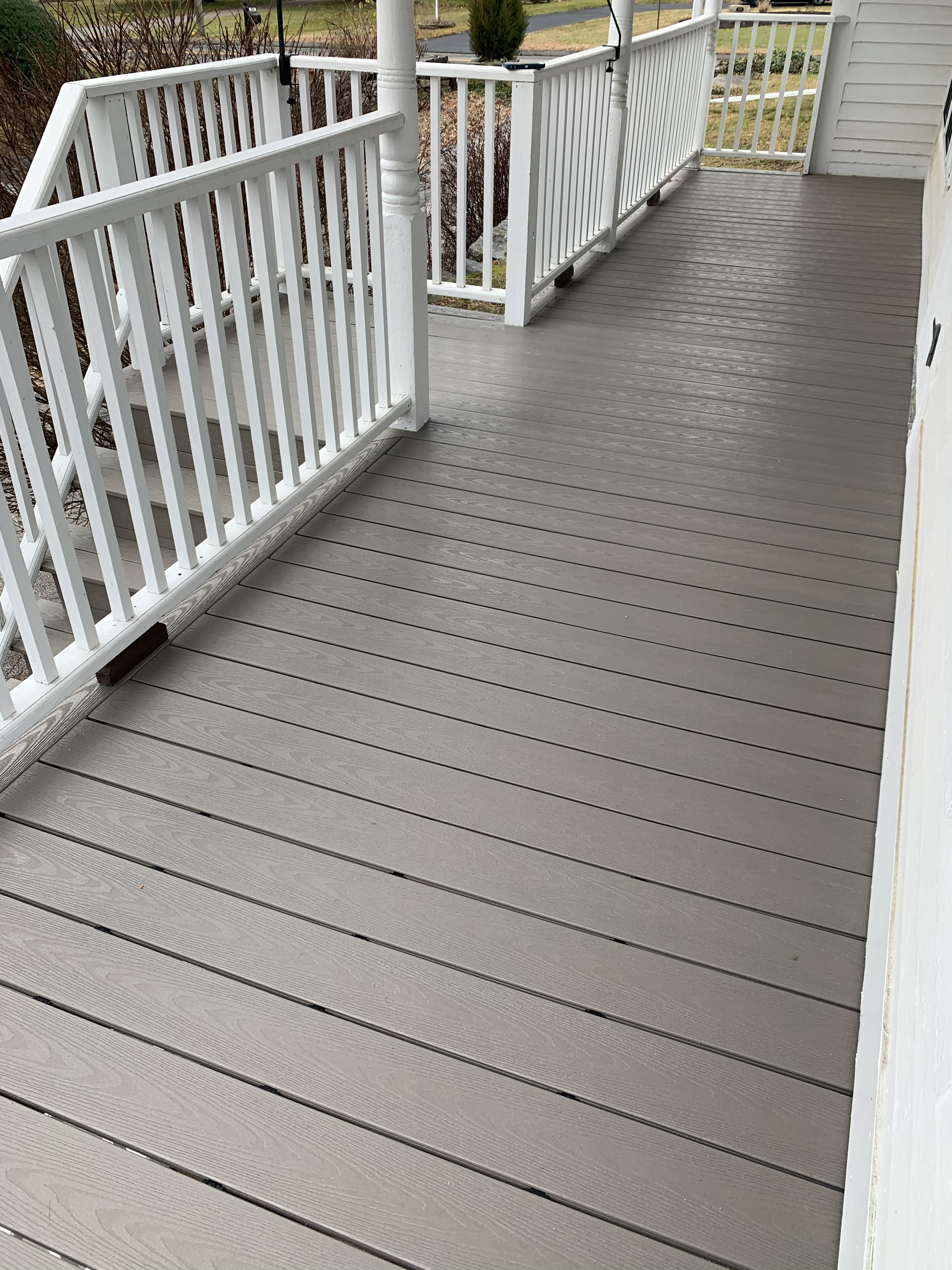Composite porch deck with white railing and steps leading down