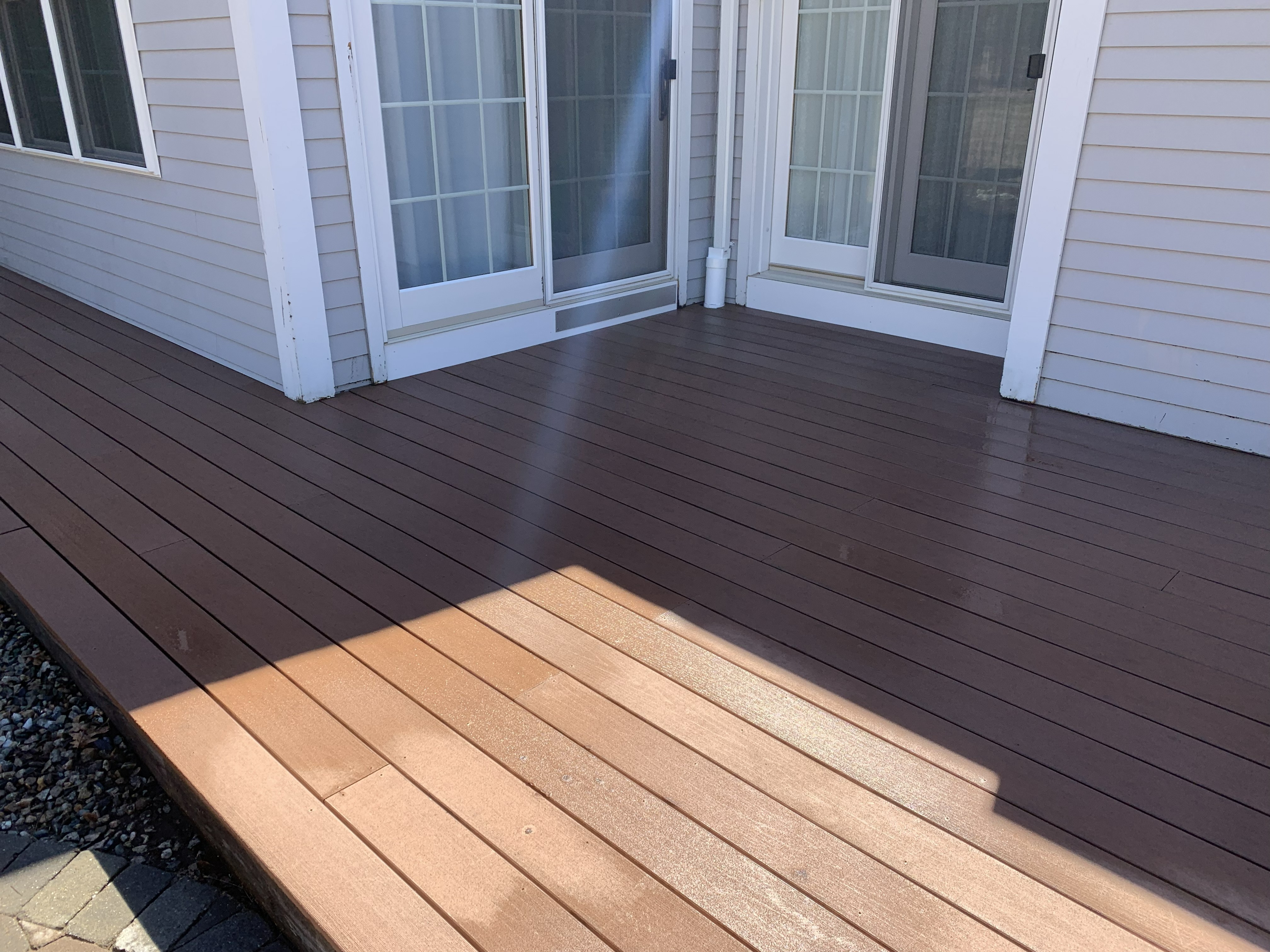 Composite deck construction with brown decking boards outside patio doors
