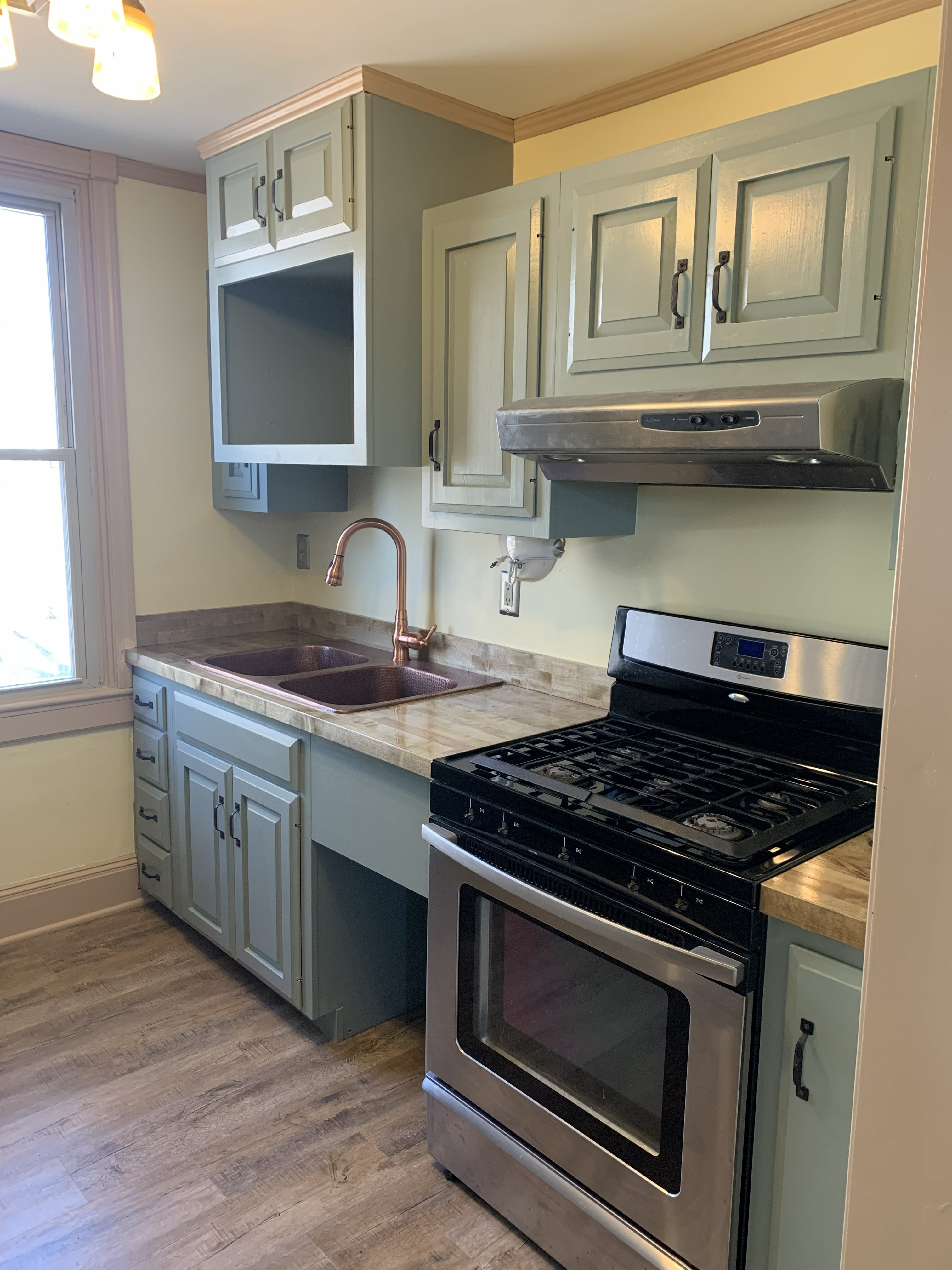 Kitchen remodel with painted cabinets, double sink, and gas range
