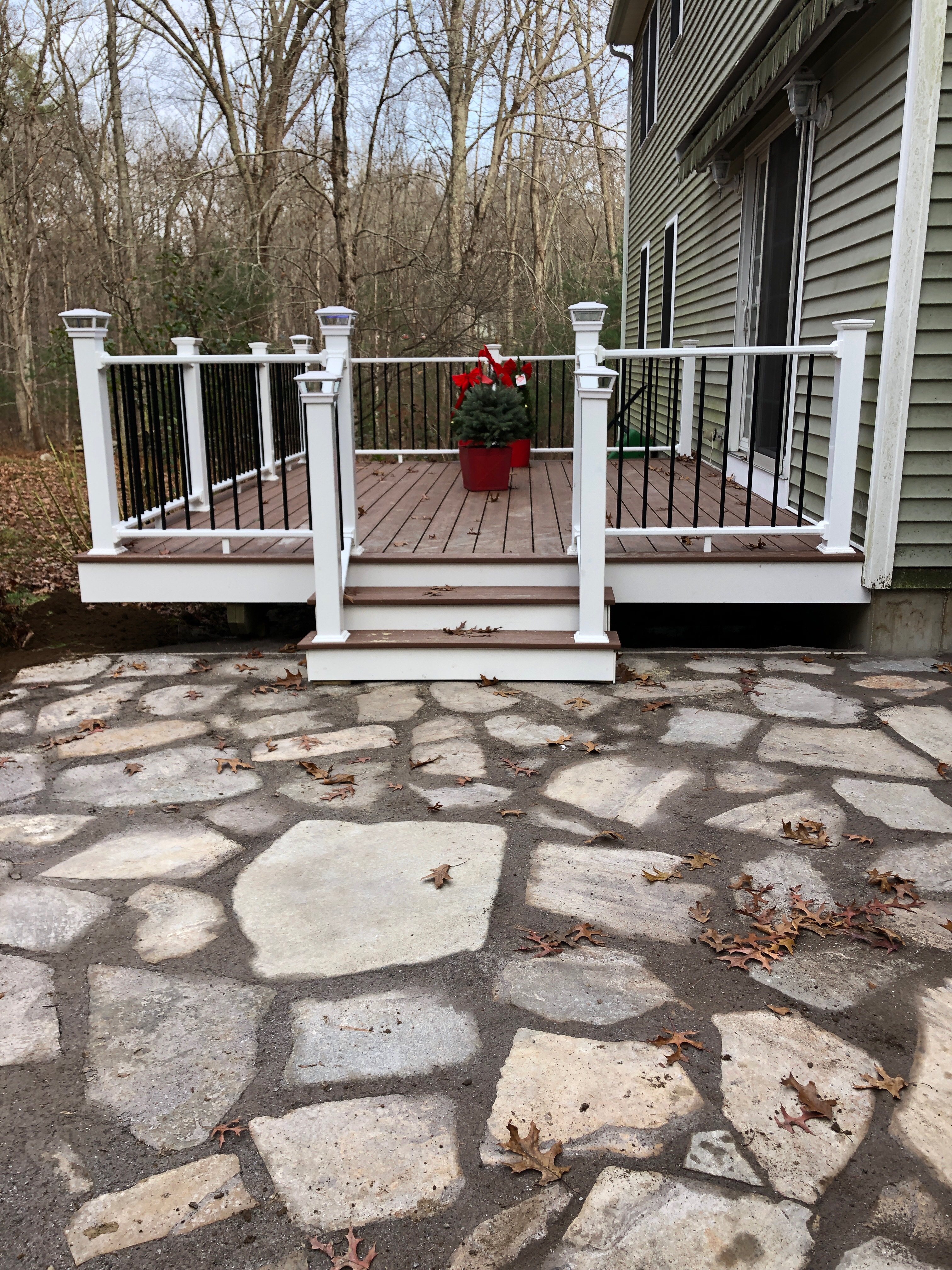 Outdoor deck with white railing and steps leading to stone patio