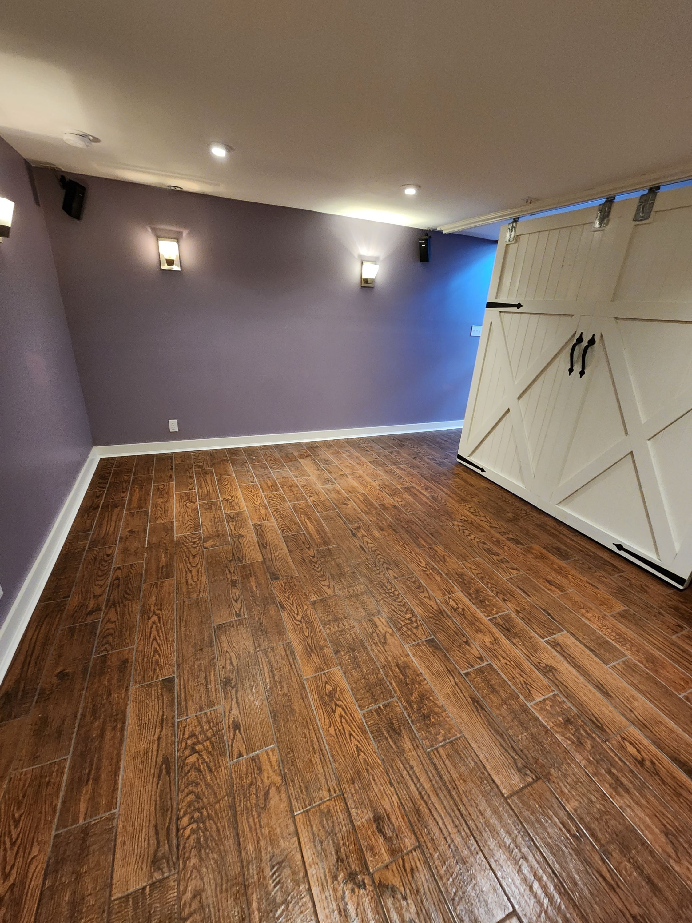 Basement remodel with wood-look tile flooring and sliding barn door feature